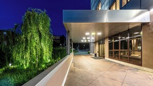 Une entrée moderne, dotée d’un passage couvert, de portes vitrées et d’un chemin bien éclairé.