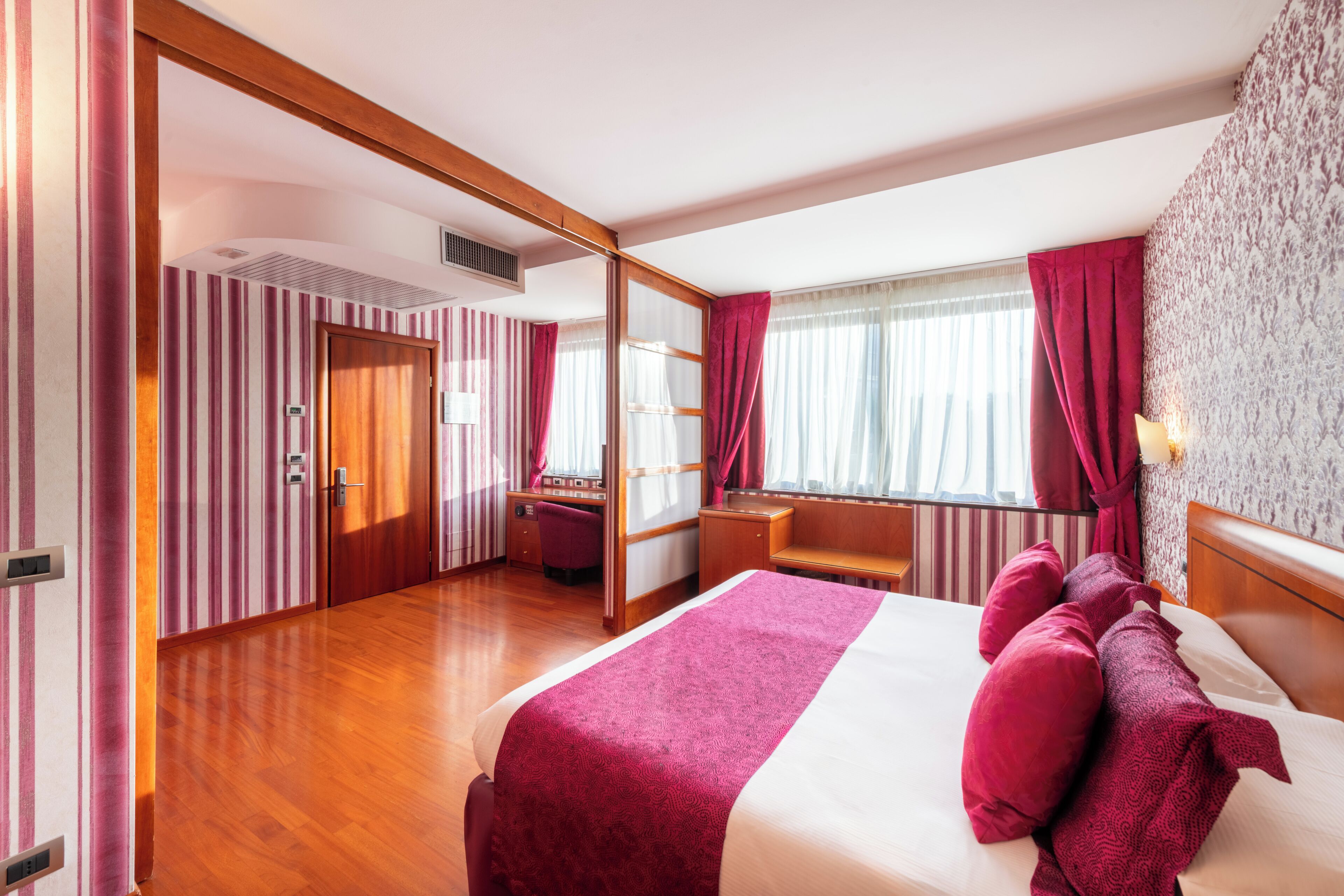 Une chambre d’hôtel avec un grand lit, un bureau et un miroir.