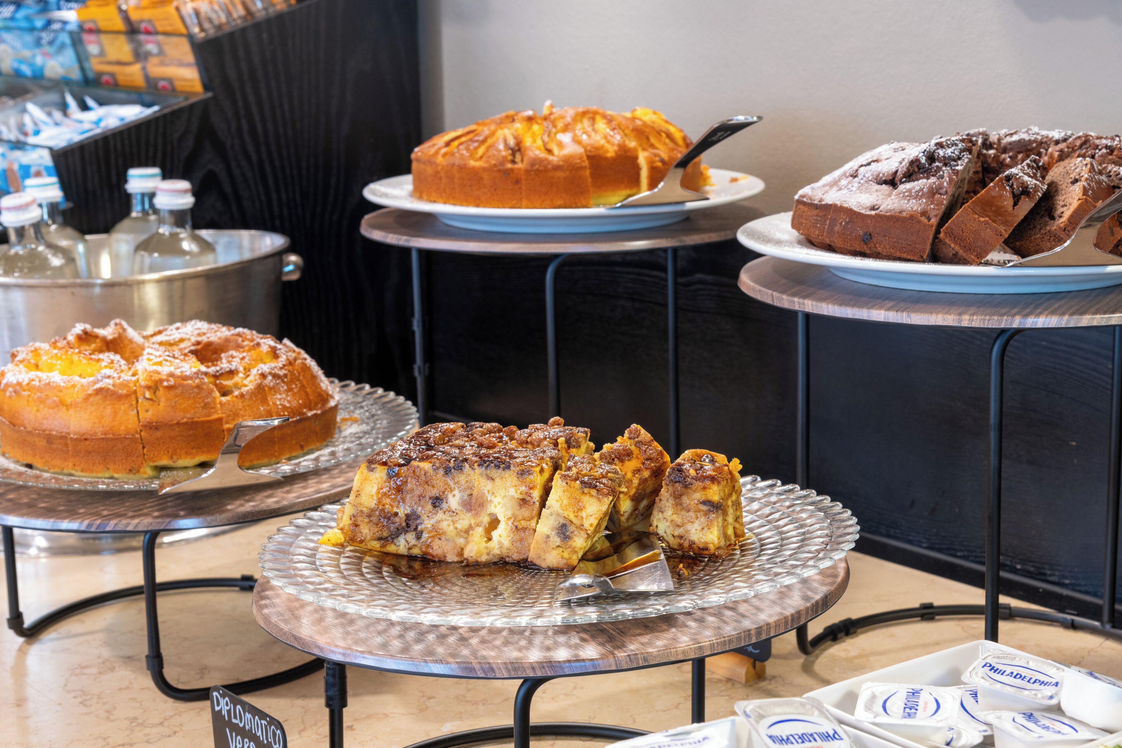 Een buffet met diverse desserts, waaronder taarten en gebak, gepresenteerd op metalen etagères.