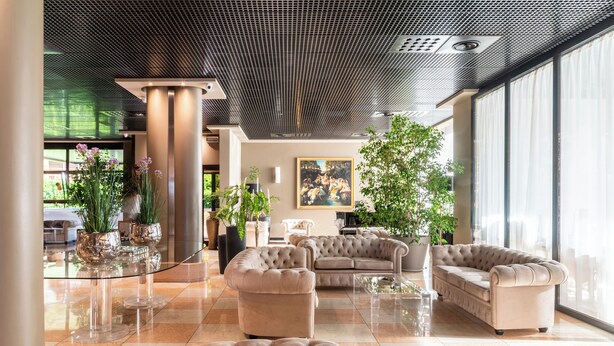 Un hall d’entrée spacieux, agrémenté d’une table basse en verre, de canapés moelleux et de grands pots de plantes.