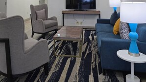 A modern living room with a sofa, armchairs, a coffee table, and a TV. - Comfort Inn Bessemer Birmingham South (Bessemer)