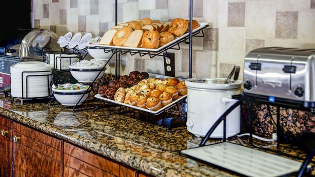 A buffet setup with various baked goods and a coffee maker. - Comfort Inn Bessemer Birmingham South (Bessemer)