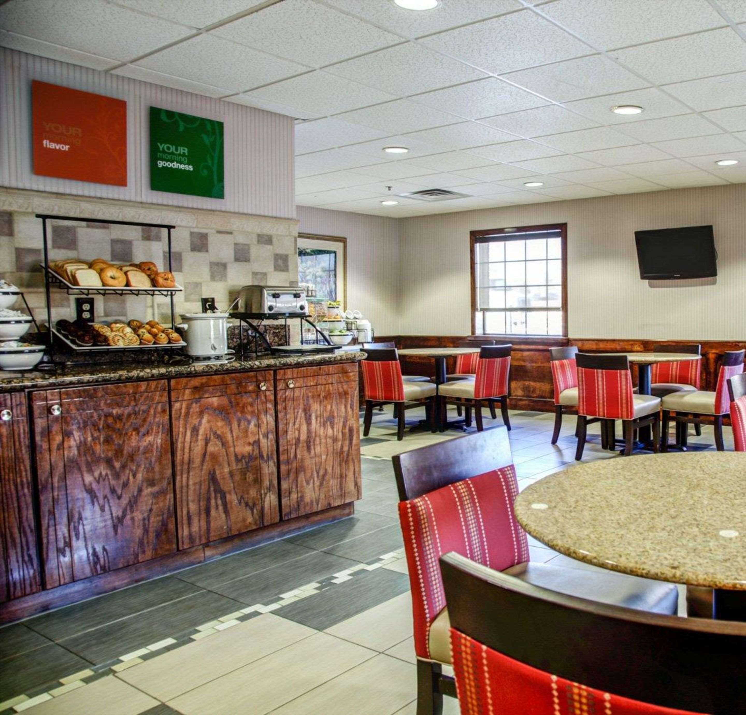A breakfast area with a buffet, seating, and a TV screen on the wall.