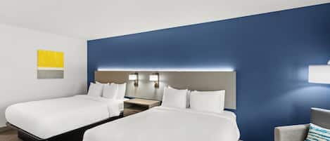 A hotel room with two beds, a desk, and a chair.