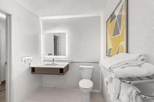 A modern bathroom with a white toilet, a sink with a mirror, and a towel rack.