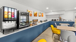 A modern kitchen with a coffee station, a refrigerator with beverage dispensers, and a counter with food items.
