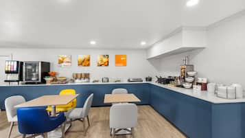 A modern kitchen with a blue accent wall, white cabinets, and a variety of appliances and utensils.