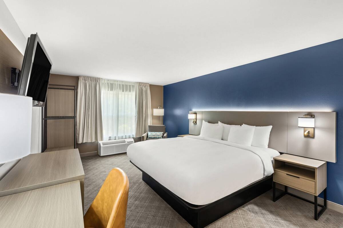 Habitación de hotel con una cama grande, mesitas de noche, un escritorio, una silla y un televisor.
