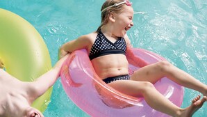 A person floating on a pink inflatable ring in a pool.