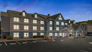 A large hotel with multiple floors, a parking lot, and an American flag.