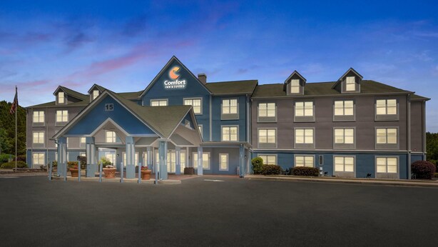 A Comfort Inn & Suites hotel with a blue exterior, multiple windows, and a well-lit entrance.