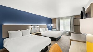 A hotel room with two beds, a desk, a chair, and a TV.