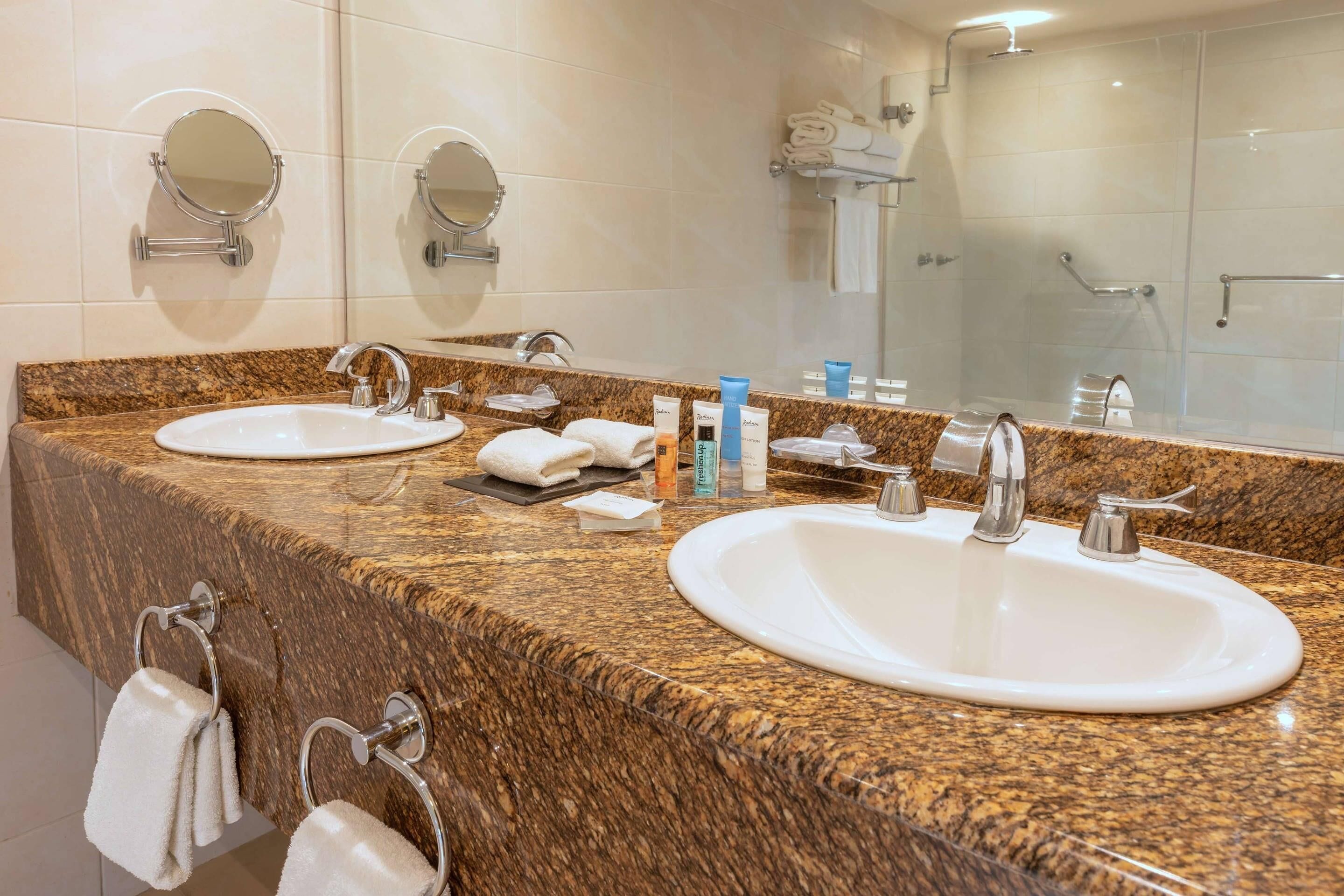 A bathroom with two sinks, a mirror, and a towel rack.