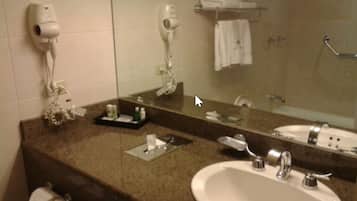 Un baño con lavamanos, espejo, toallero y secador de pelo.