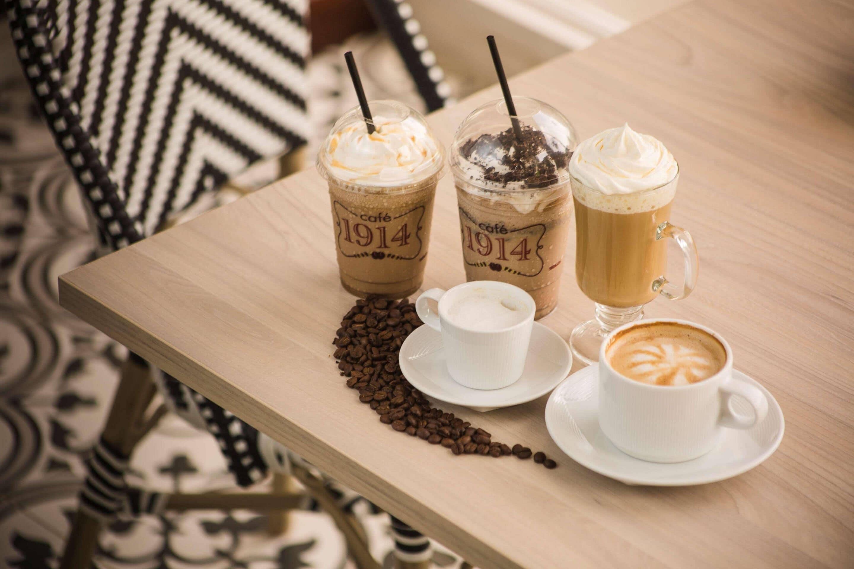 Une table avec trois boissons au café glacé, une tasse blanche et une soucoupe.