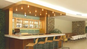 Una zona de bar con mostrador, taburetes y un área de estar con mesas y sillas.