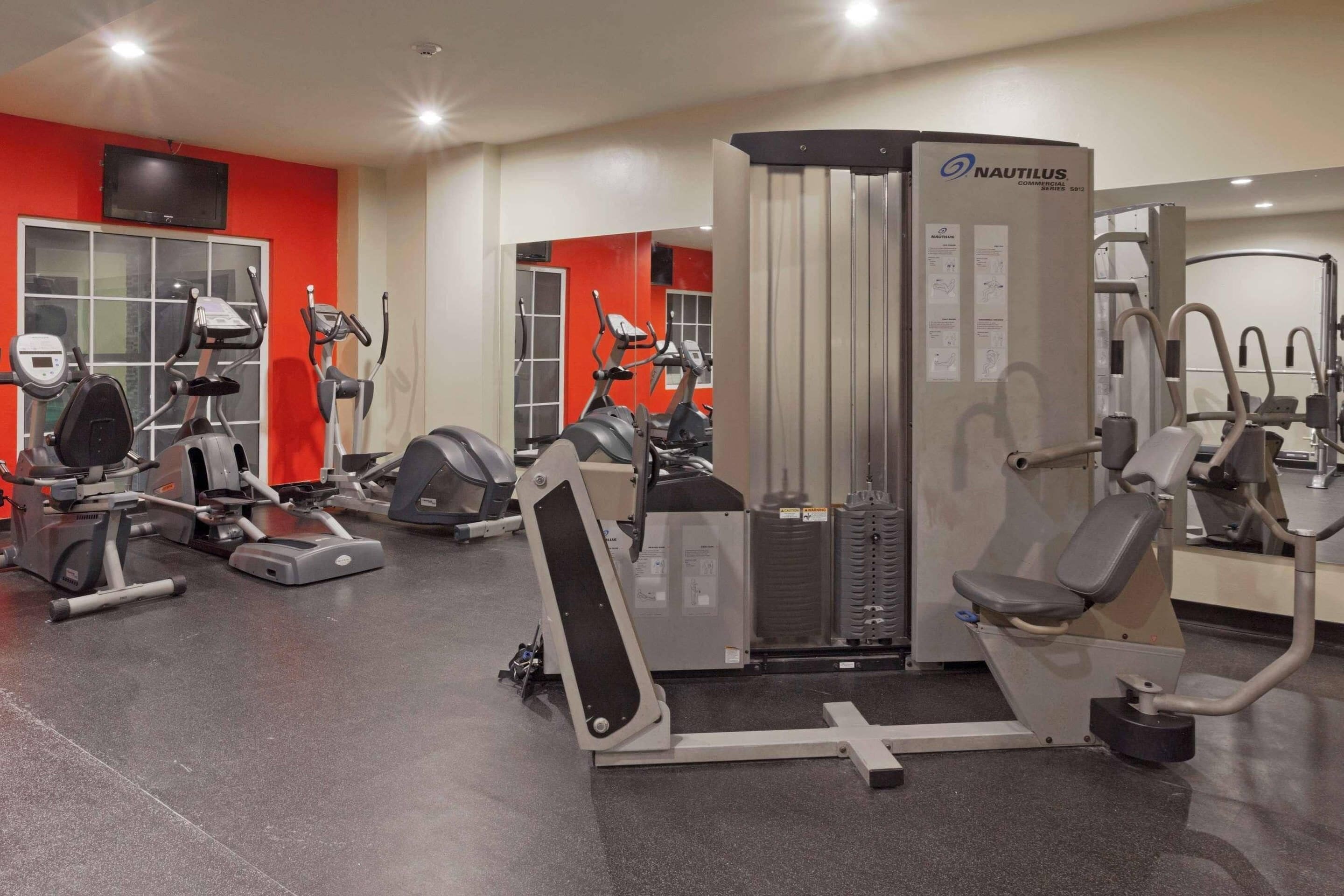 Un gimnasio con equipo Nautilus, cintas de correr y bicicletas estáticas.