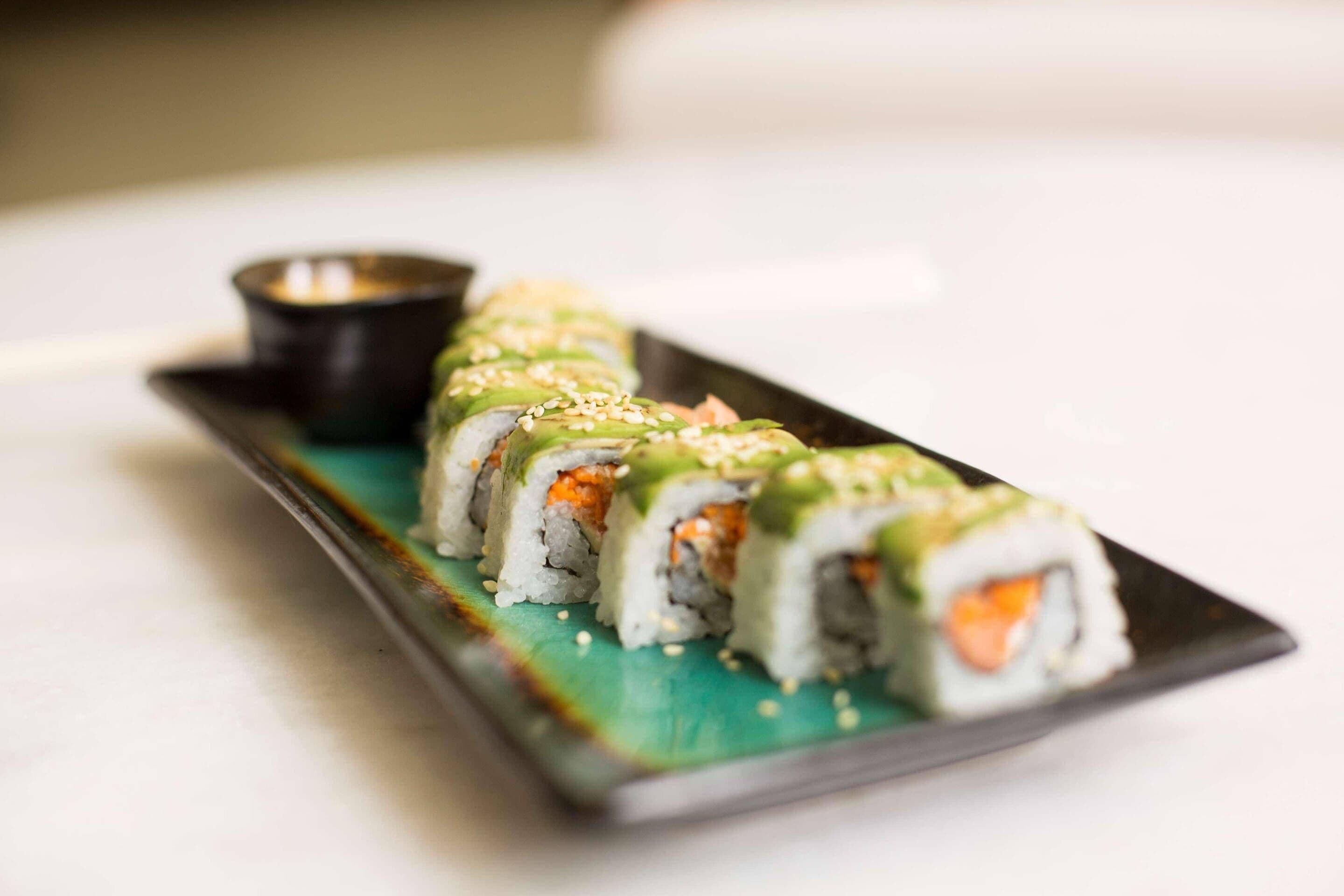 Un plato de sushi acompañado de salsa para mojar.