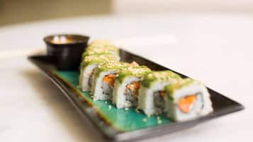 A sushi dish with a side of dipping sauce on a rectangular plate.