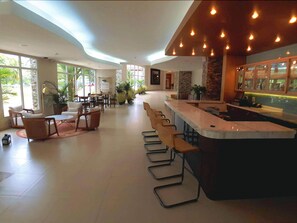 A spacious indoor area with a long bar, seating arrangements, and large windows allowing natural light. - Radisson Hotel Panama Canal (Panama City)