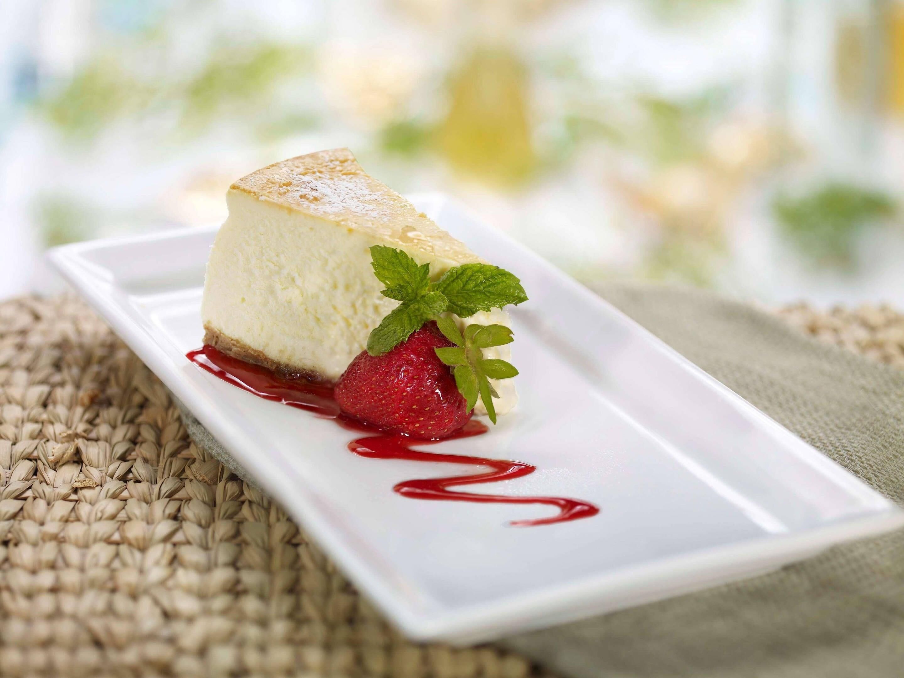 A dessert on a white plate with a berry garnish and a red sauce.