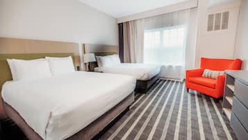 A hotel room with two beds, a sofa, a desk, and a window with curtains.