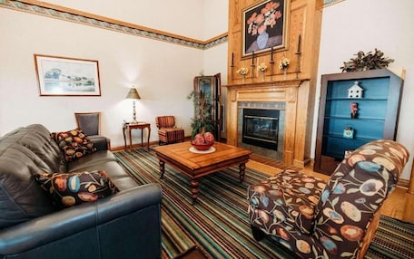A living room with a fireplace, leather sofa, patterned armchair, and a blue shelving unit.