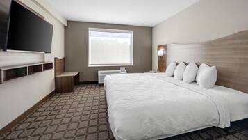 Habitación de hotel con una cama grande, televisión de pantalla plana, ventana y estante empotrado.