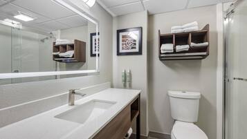 Un baño moderno con un espejo grande, un lavabo, un inodoro y una ducha.