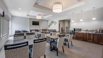 A modern dining area with multiple tables and chairs, a stone accent wall, and a buffet counter.