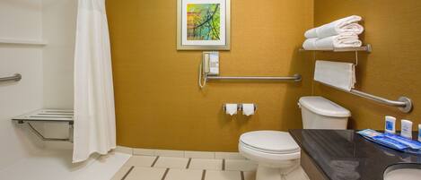 A bathroom with a toilet, sink, towel rack, and a framed picture on the wall.