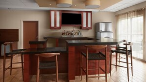 Een moderne keuken met een centraal eiland, barstoelen en een flatscreen televisie die boven het eiland is bevestigd.