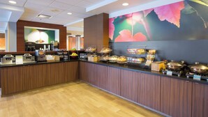 Een buffetgedeelte met een houten toonbank, diverse foodstations en een grote bloemenmuur.