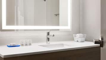 A modern bathroom with a large mirror, a white sink, and a towel rack.