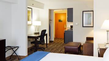 Een hotelkamer met een bed, bureau, stoel en een kleine kitchenette.