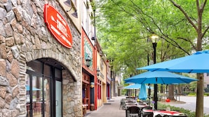 A stone building with a sign for 'Sweets' and outdoor seating with blue umbrellas. - Holiday Inn Express & Suites Greenville - Downtown by IHG (Greenville)