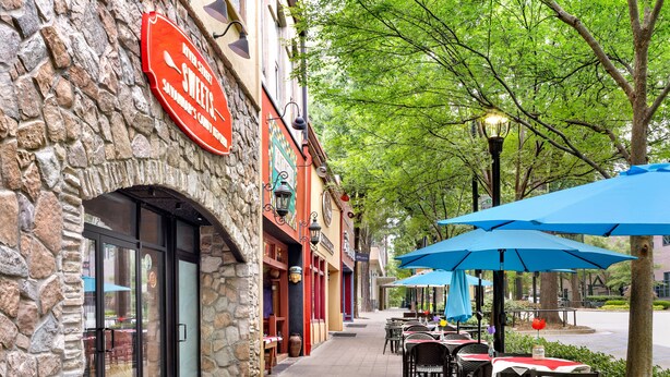 A stone building with a sign for 'Sweets' and outdoor seating with blue umbrellas. - Holiday Inn Express & Suites Greenville - Downtown by IHG (Greenville)