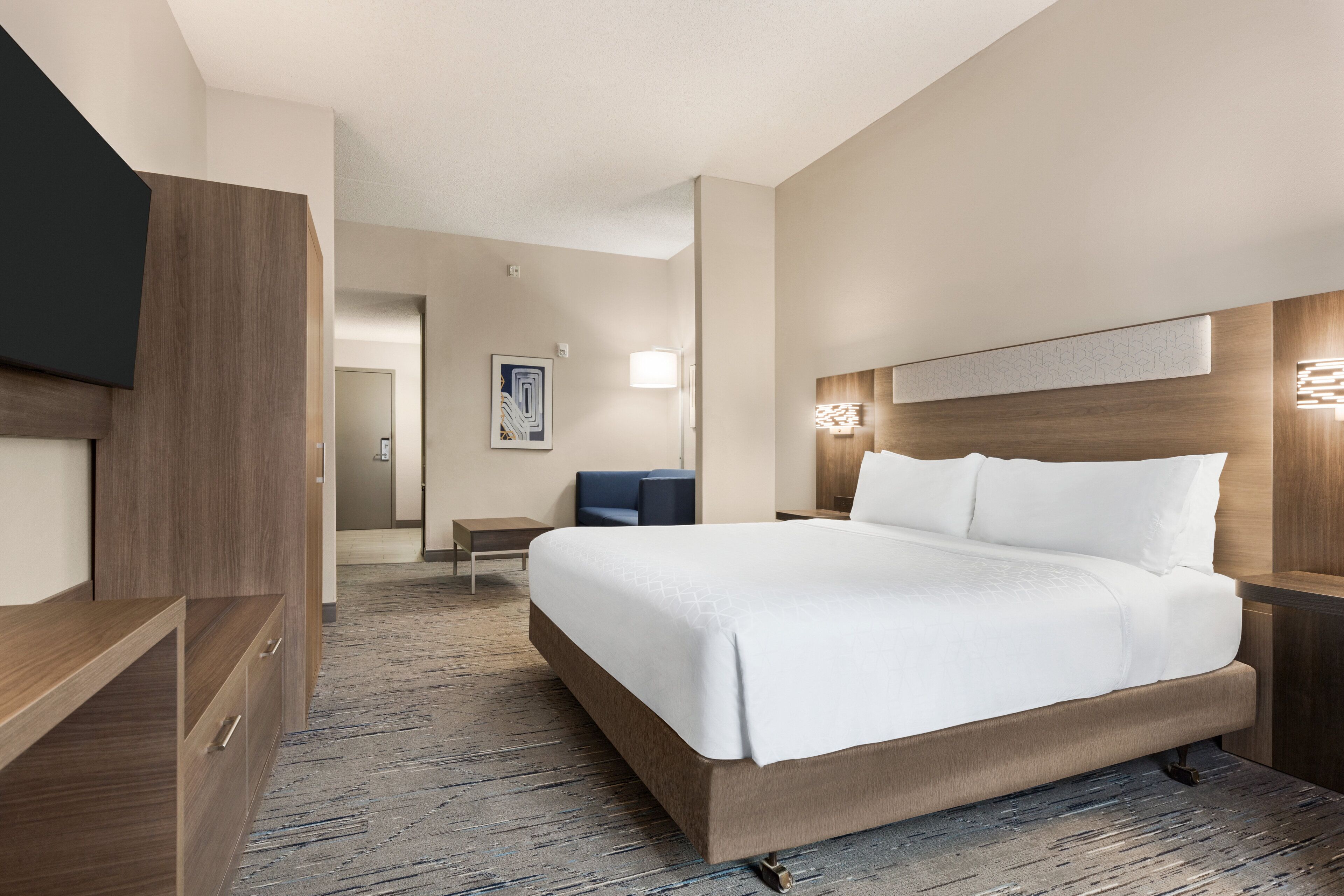 A hotel room with a large bed, a TV, a desk, and a chair.