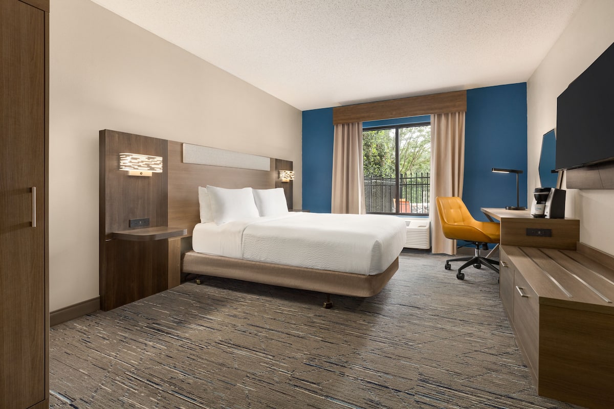 Una habitación de hotel con una cama, un escritorio, una silla y un televisor.