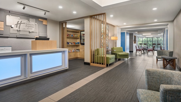 A hotel lobby with a reception desk, seating area, and a view of the outdoors. - Holiday Inn Express & Suites Greenville - Downtown by IHG (Greenville)