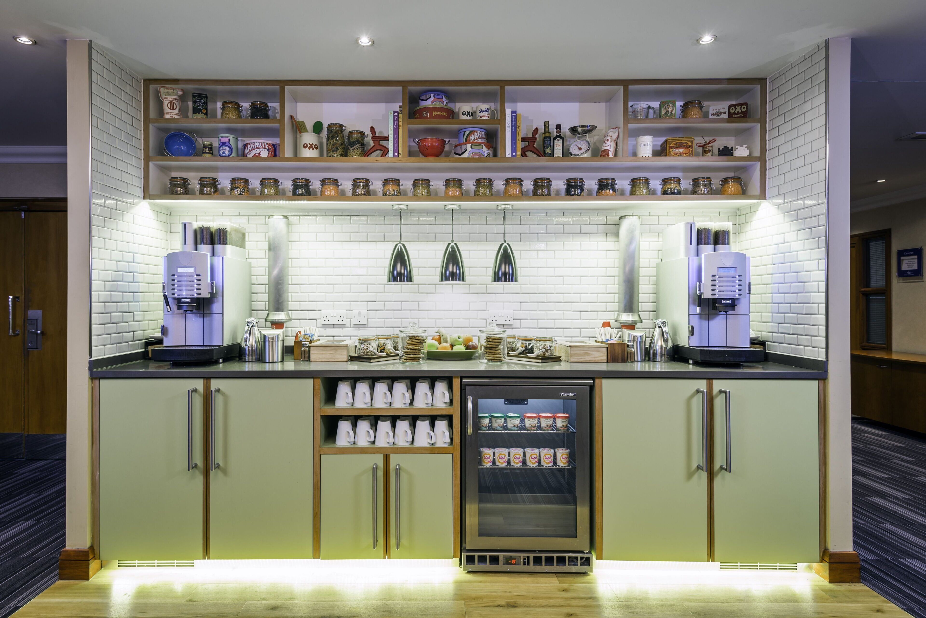 A modern kitchen with built-in appliances, a coffee station, and a variety of jars on shelves.