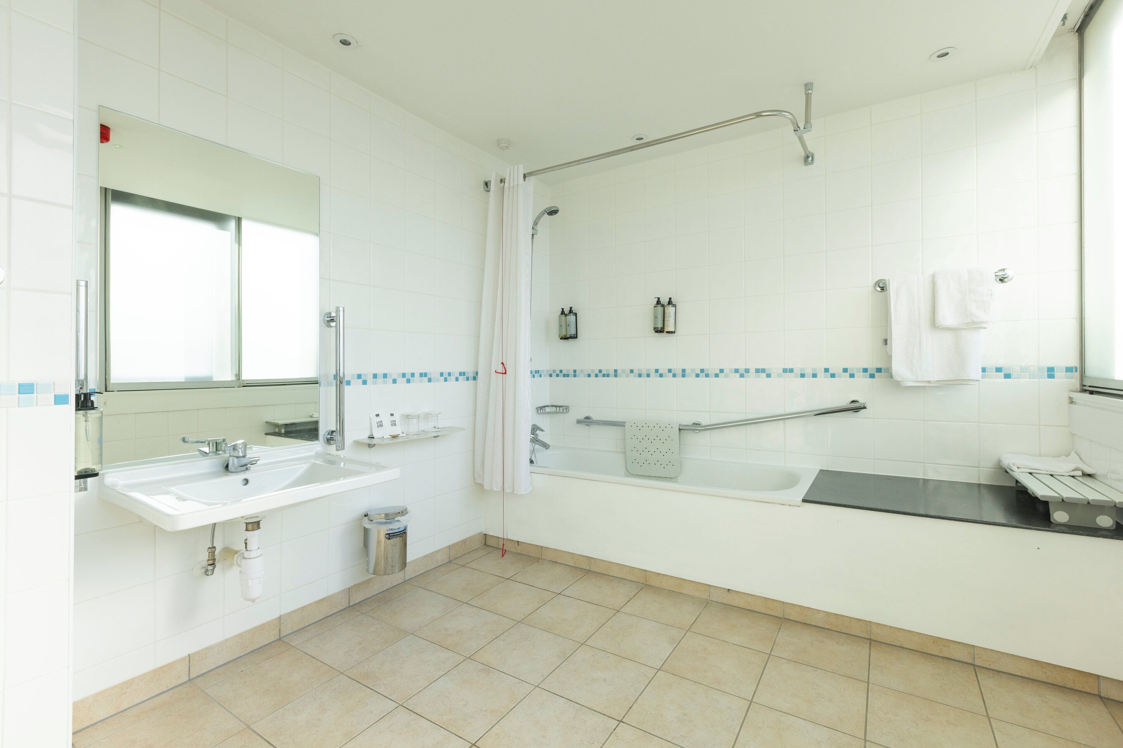 A modern bathroom with a sink, mirror, shower, and bathtub.