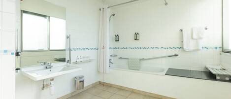 A modern bathroom with a sink, mirror, shower, and bathtub.