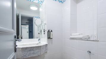 Un baño moderno con lavamanos de mármol, un espejo, ducha y toallero.