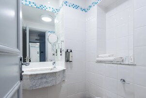 Un baño moderno con lavamanos de mármol, un espejo, ducha y toallero.