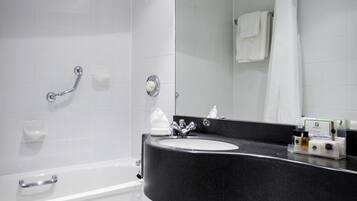 Um banheiro moderno com pia de bancada preta, vaso sanitário branco, chuveiro com porta de vidro e espelho sobre a pia.