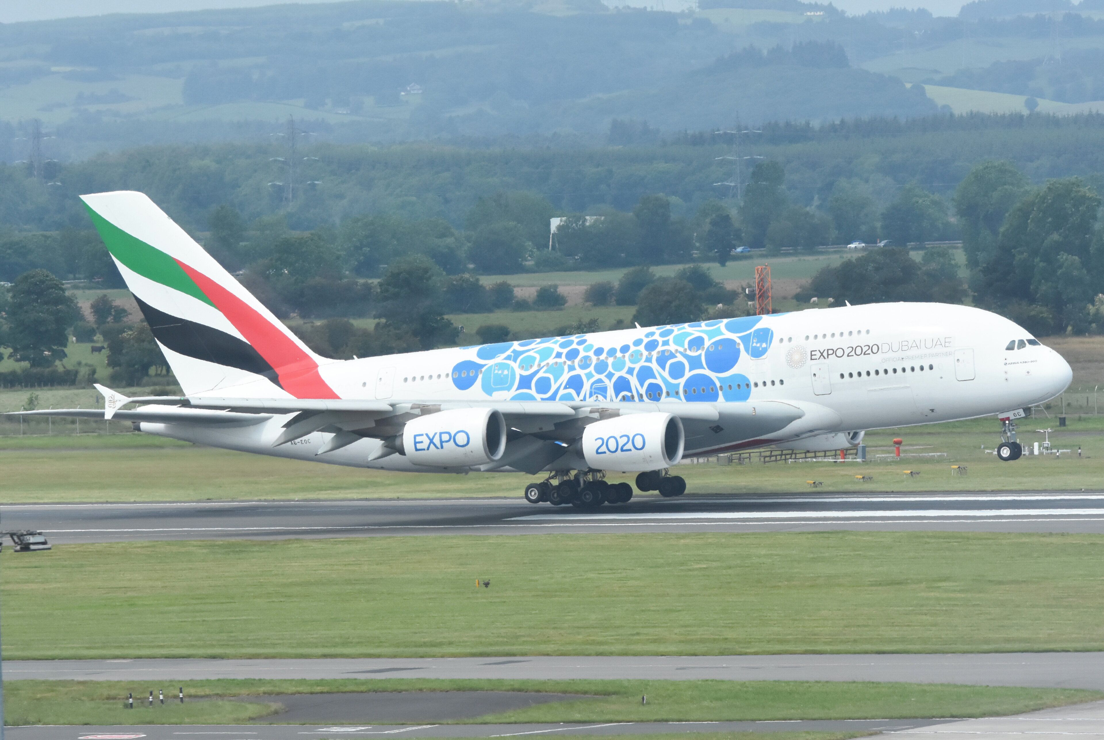 Un avión comercial grande con 'EXPO 2020' y 'DUBAI JAE' en su fuselaje, avanzando por una pista de aterrizaje.