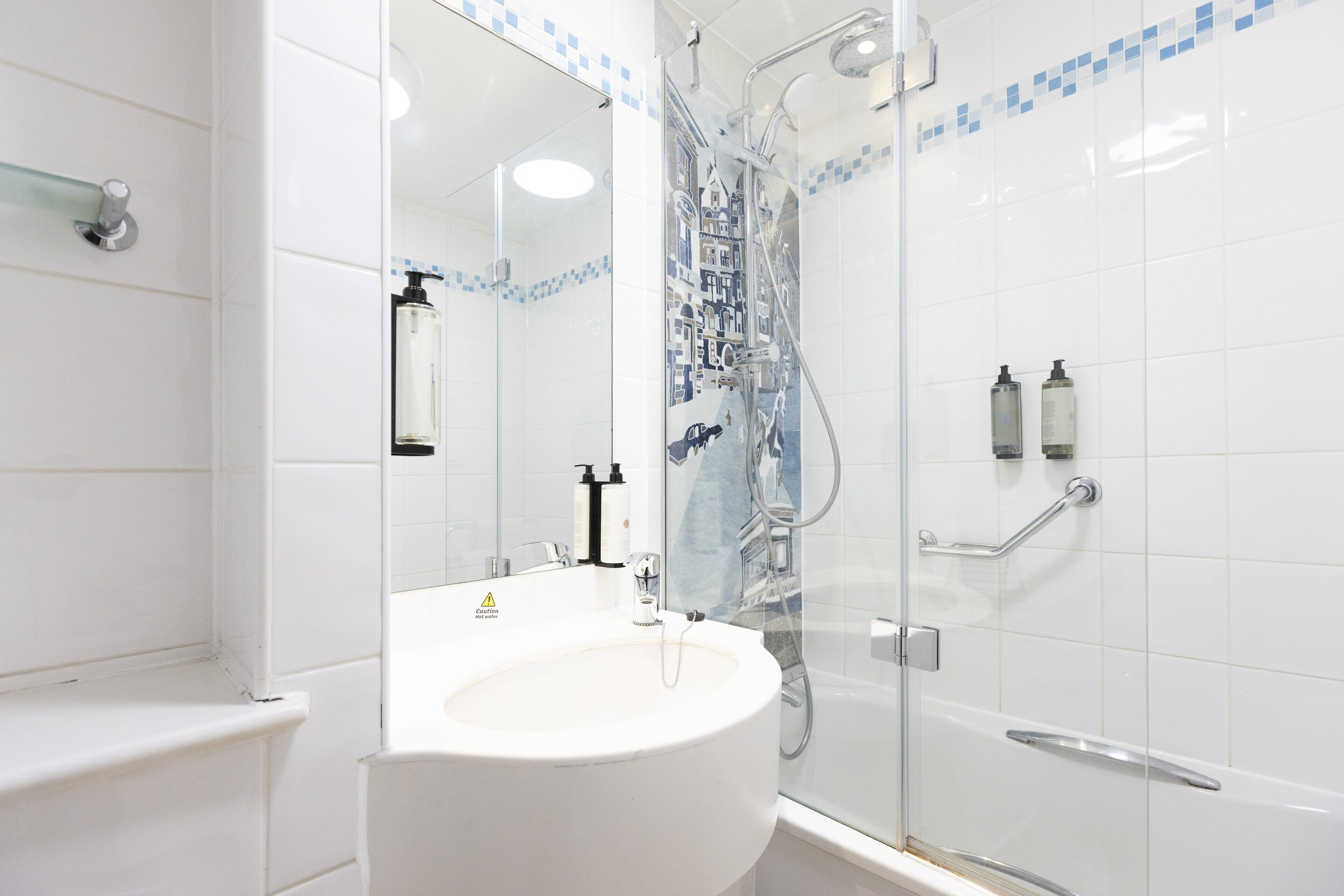 A modern bathroom with a glass-enclosed shower, a white sink, and a mirror.