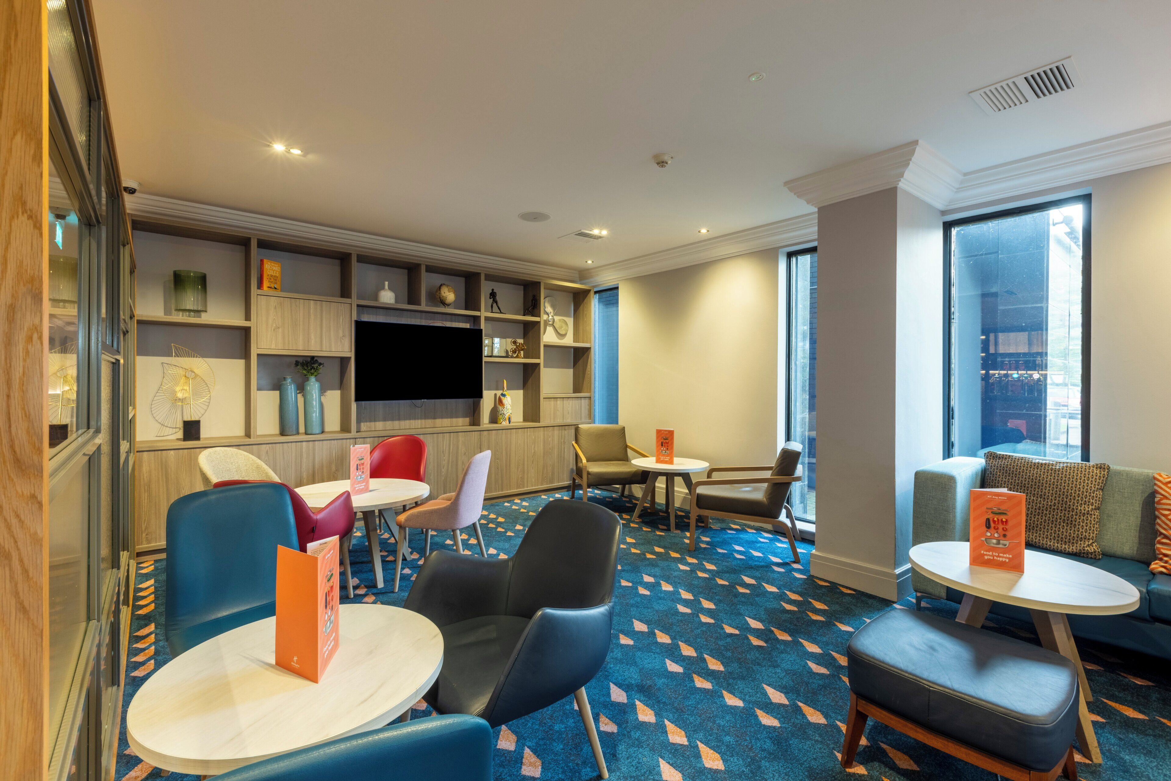 Eine Hotelhalle mit Sitzbereichen, einem Fernseher und einem großen Fenster.