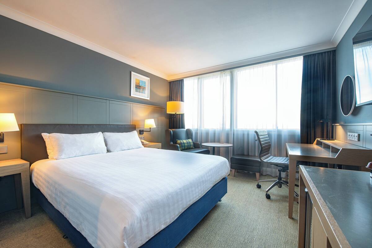 Une chambre d’hôtel avec un grand lit, un bureau, une chaise et une petite table.